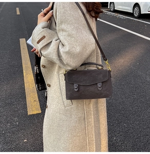 Detail of vintage matte leather crossbody bag with dual round buckles and hand strap