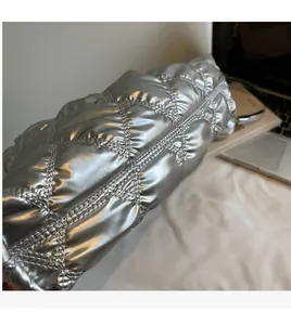 Close-up of shiny silver quilted handbag with metallic finish and puffer diamond pattern