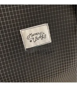 Close-up detail of the black plaid fabric and the white Maran BAGS logo label on the tote