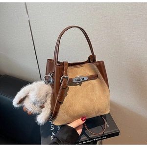 Dettaglio borsa a secchiello vintage con cuciture in pelle scamosciata e ciondolo coniglio