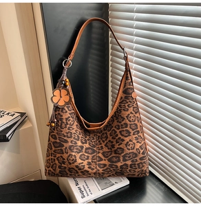 Detail of leopard print hobo bag with brown strap and orange flower pendant charm