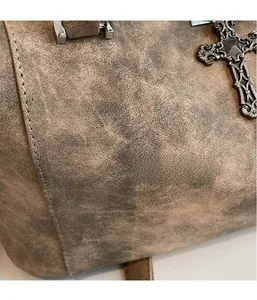Dettaglio in finta pelle marrone vintage con ciondolo a croce e cuciture su una borsa