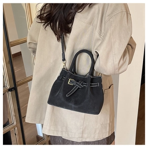 Detailed shot of black suede handbag with white stitching and stylish buckle detail