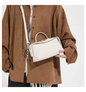 Detail of cream white leather crossbody bag with silver zipper and ergonomic handle