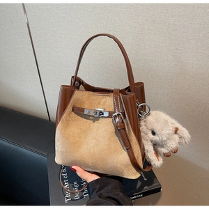 Dettaglio di una borsa a secchiello bicolore con chiusura a scatto e ciondolo a coniglio