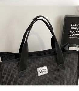 Close-up of black and white checkered canvas tote bag with Muran BAGS brand embroidery