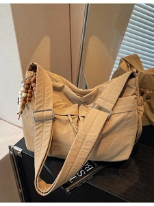 Minimalistische beige Nylon-Umhängetasche mit breitem Gurt und Perlenanhänger-Dekoration