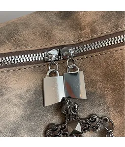 Dettaglio borsa in pelle marrone con cerniera argento e ciondolo croce gotica