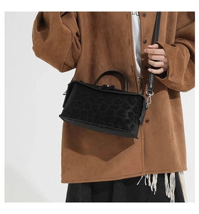 Détail du sac à main en daim noir avec imprimé léopard porté par un mannequin