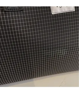Macro shot of black checkered ripstop fabric with silver label and woven strap