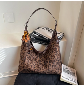 Close-up of leopard print hobo bag with wood bead and leather flower pendant