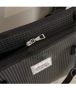 Close-up of black checkered tote bag with silver metal zipper and brand woven label
