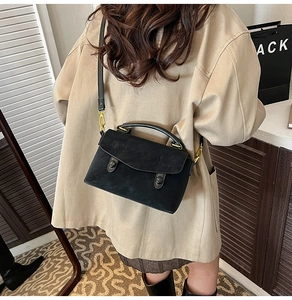 Detail of black vintage crossbody bag with gold hardware and two round buckle accents