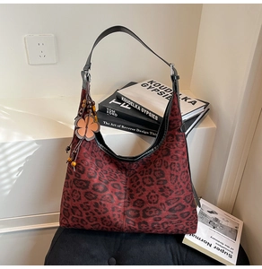 Detail of red leopard print hobo bag with floral charm and black leather trim