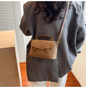 Detail of brown vintage crossbody bag with flap and decorative buttons on wool blazer