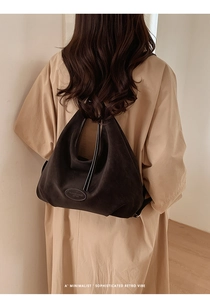 Braune Vintage-Wildledertasche an einem Modell im beigen Mantel aus der Rückansicht