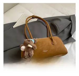 Détail d'un sac Boston marron en similicuir avec charm ours et logo de marque gravé