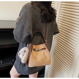 Dettaglio borsa a secchiello vintage marrone con ciondolo di peluche e chiusura a scatto