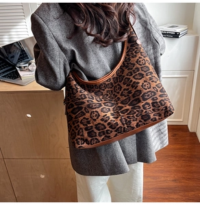 Spacious leopard print hobo bag with brown leather trim styled on a professional model