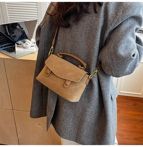 Detail of vintage brown matte PU leather crossbody bag with flap and decorative buckles