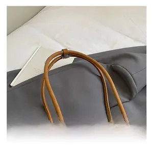 Détail du sac vintage marron montrant les longues anses et le pendentif ours mignon