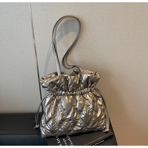 Detail of champagne gold quilted bucket bag with metallic texture and drawstring closure