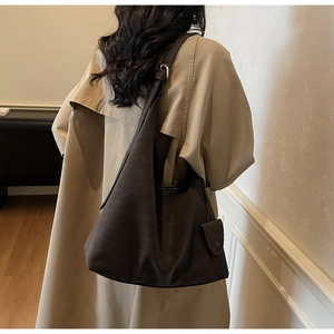 Detail of dark brown matte leather tote bag with silver buckle and adjustable shoulder strap