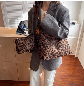 Detail of leopard print hobo bag with brown leather strap and floral charm accessory