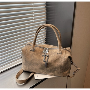 Dettaglio della borsa in pelle marrone vintage con ciondolo a croce e tracolla