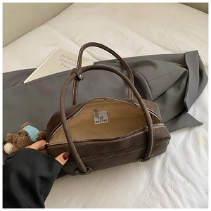 Détail du sac Boston en daim marron avec surpiqûres blanches et pendentif ours