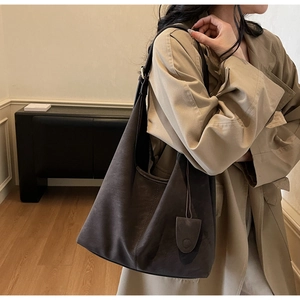 Detail of dark brown suede tote bag with minimalist hanging tassel decoration