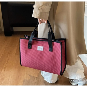 Detail shot of pink checkerboard tote bag with durable black handles and logo label