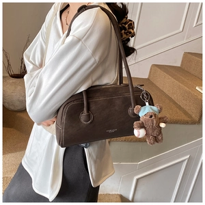 Détail du sac à main en daim marron foncé avec pendentif ours et logo de mode imprimé