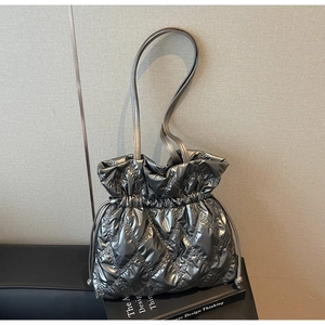 Detail of silver metallic quilted puffer tote bag with drawstring closure and slim straps