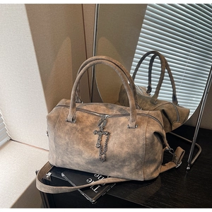 Dettaglio della borsa marrone vintage con ciondolo a croce e finitura testurizzata