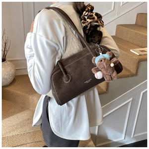 Détail du sac Boston en daim marron foncé avec surpiqûres blanches et ours en peluche