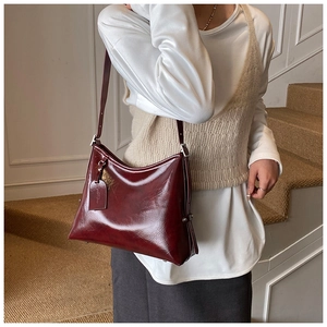 Chic burgundy oil wax leather bucket bag worn over shoulder in a lifestyle setting