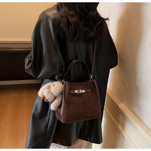 Dettaglio borsa a secchiello marrone vintage con chiusura a scatto e ciondolo in peluche