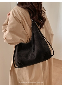 Detailansicht der schwarzen Vintage-Wildledertasche getragen über einem beigen Mantel