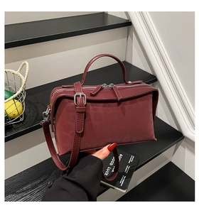 Sac bandoulière rouge foncé avec double fermeture éclair et bandoulière réglable sur escalier