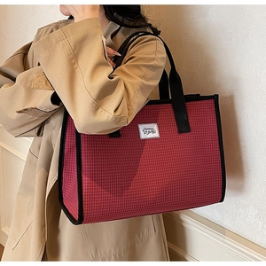Détail du sac cabas à carreaux rouges avec lanières noires et étiquette Memory Bag