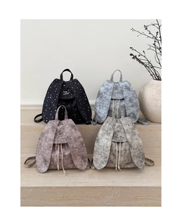 Chic rabbit ear backpacks in four pastel colors displayed on minimalist stone steps