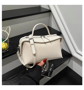 Détail du sac bandoulière crème avec double fermeture éclair et bandoulière réglable