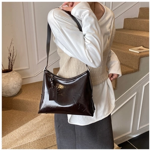 Detail of glossy deep brown leather shoulder bag with sleek minimalist texture