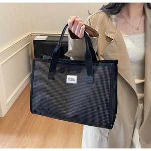 Détail d'un sac cabas à carreaux noir et blanc porté par un mannequin dans un cadre moderne