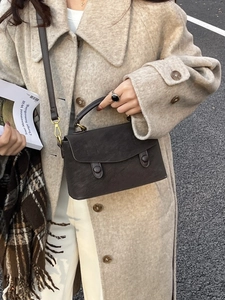 Deep brown matte leather crossbody bag with round buckles worn with winter wool coat