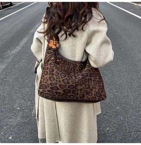 Detail of leopard print tote bag with wooden beads and flower charm on shoulder strap