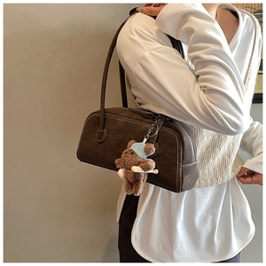 Détail du sac bandoulière en daim marron foncé avec un charmant pendentif ours peluche
