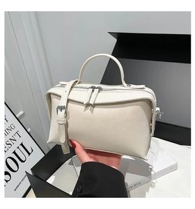 Détail de la double fermeture éclair en métal et de la poignée ronde du sac en cuir PU crème
