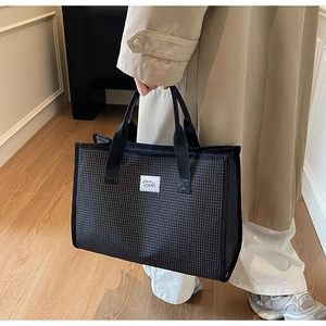 Détail du sac cabas en toile à carreaux avec poignées renforcées et écusson de la marque